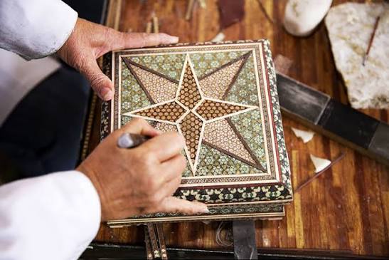 Artisan working on a khatam marquetry box with a star motif