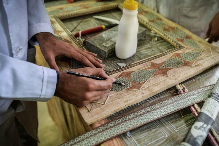 Artisan marking a khatam frame during marquetry work